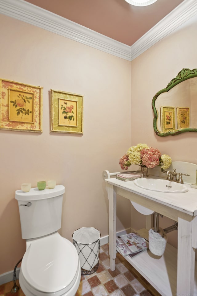 bathroom with tile patterned flooring, toilet, ornamental molding, and sink