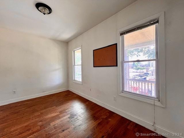 unfurnished room with baseboards, dark wood finished floors, and a wealth of natural light