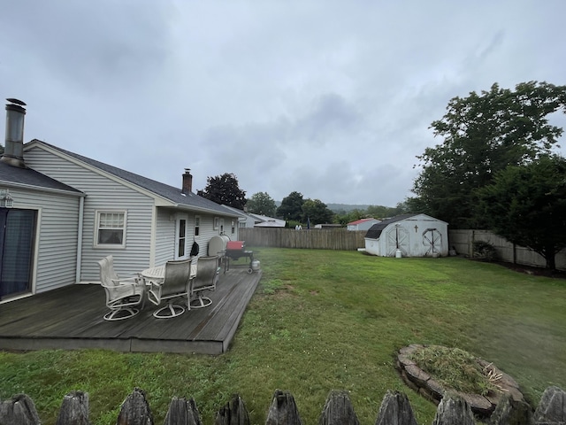 view of yard with an outbuilding, a fenced backyard, a deck, and a storage unit