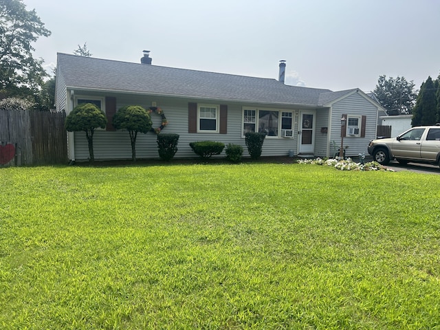 ranch-style house with a shingled roof, fence, and a front lawn