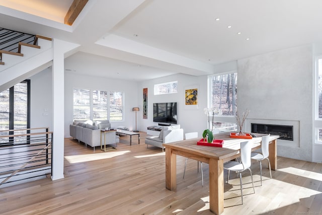 recreation room featuring light wood-type flooring, beam ceiling, and a large fireplace