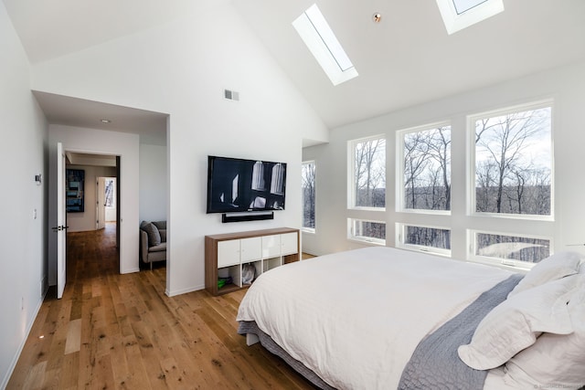 bedroom featuring high vaulted ceiling, wood-type flooring, multiple windows, and a skylight