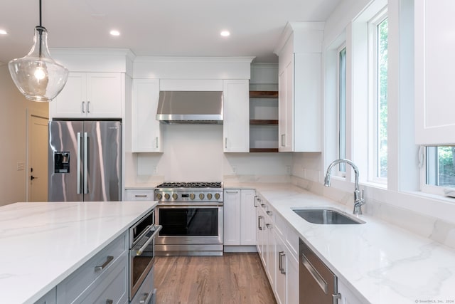 kitchen featuring a wealth of natural light, light wood-type flooring, wall chimney range hood, and appliances with stainless steel finishes