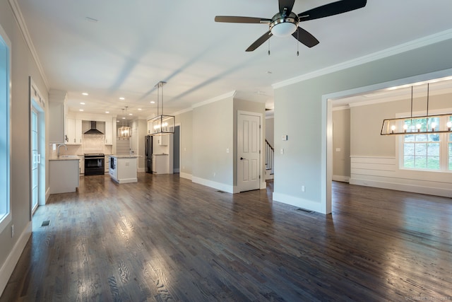 unfurnished living room featuring ceiling fan with notable chandelier, dark wood-type flooring, and crown molding