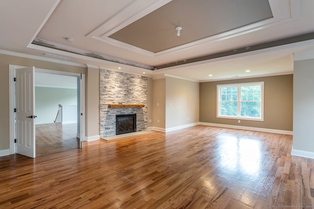 unfurnished living room with a tray ceiling, a fireplace, crown molding, and wood-type flooring