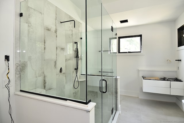 bathroom with a shower with door, vanity, and tile patterned floors