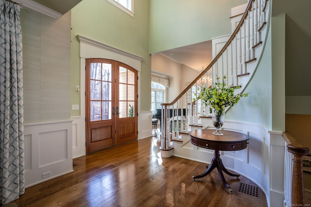 foyer entrance featuring ornamental molding, dark wood-type flooring, french doors, and a healthy amount of sunlight