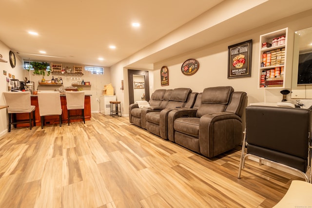 cinema room with light hardwood / wood-style flooring and indoor bar