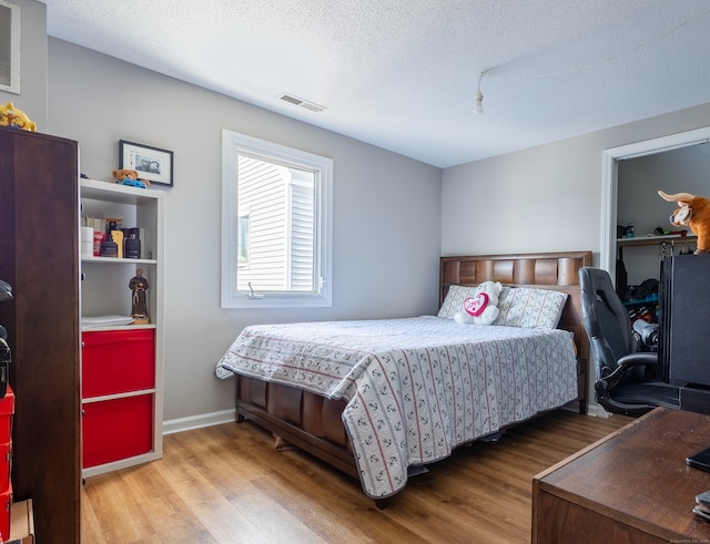 bedroom with a textured ceiling and hardwood / wood-style floors