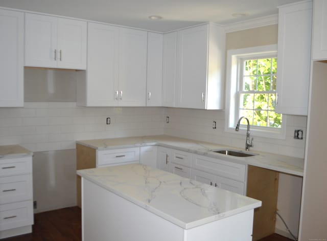 kitchen with light stone counters, sink, decorative backsplash, and white cabinets