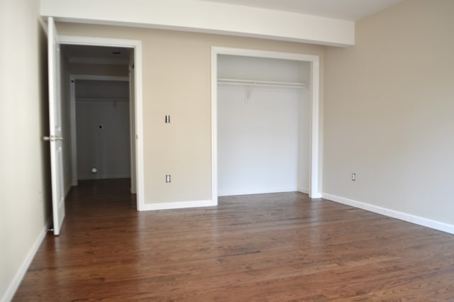 unfurnished bedroom with dark wood-type flooring and a closet