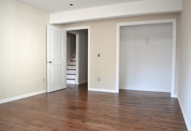 unfurnished bedroom featuring dark wood-type flooring and a closet