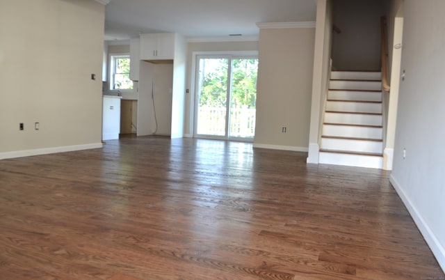 unfurnished living room with dark hardwood / wood-style flooring and crown molding