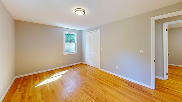 unfurnished bedroom with light wood-type flooring and a closet