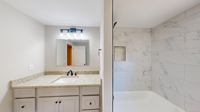 bathroom with tiled shower / bath and vanity