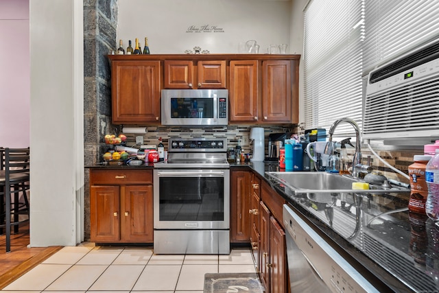 kitchen featuring decorative backsplash, light tile patterned floors, dark stone countertops, sink, and stainless steel appliances