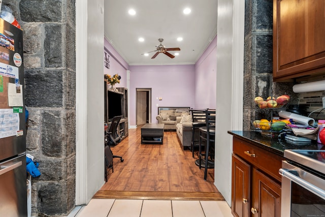 kitchen with tasteful backsplash, light hardwood / wood-style floors, ceiling fan, stainless steel stove, and ornamental molding