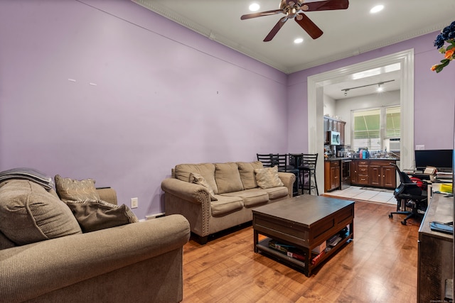 living room featuring light hardwood / wood-style floors, ornamental molding, and ceiling fan