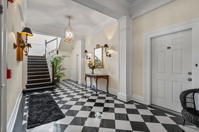 foyer entrance with ornamental molding, decorative columns, and a notable chandelier