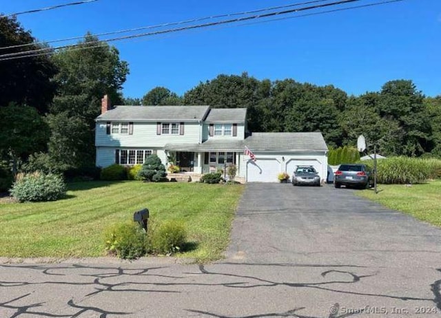 view of front of home with driveway, an attached garage, a chimney, and a front lawn