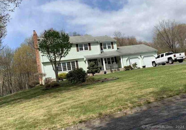 view of front of home with a front lawn, covered porch, and an attached garage