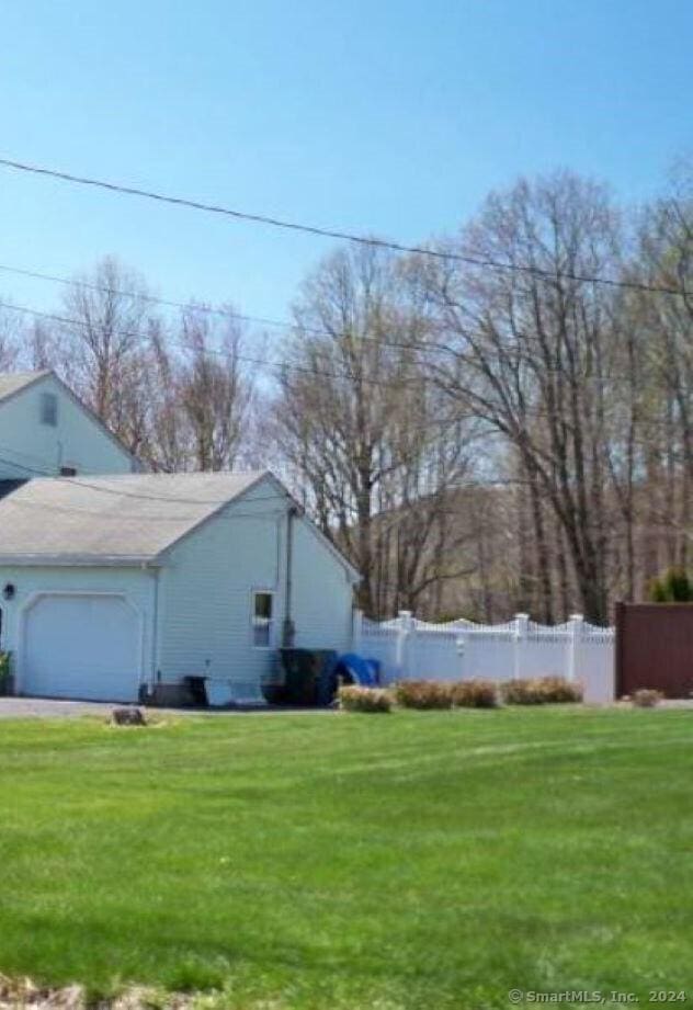 view of yard featuring an attached garage, fence, and driveway