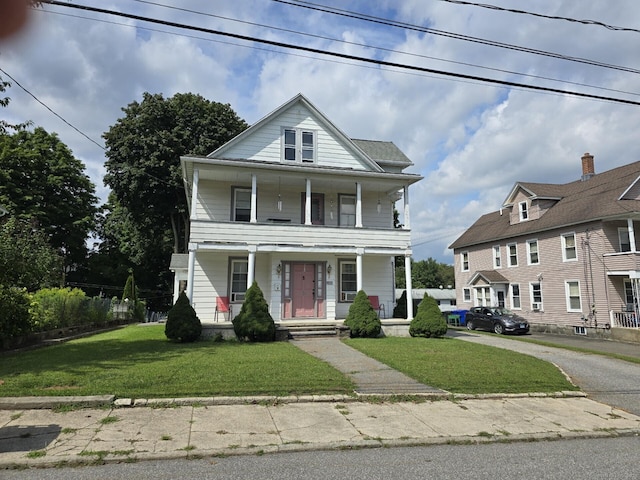 view of front facade with a balcony, a porch, and a front yard