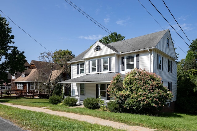 view of front of house featuring a porch, a front yard, and a shingled roof