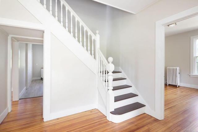 staircase featuring baseboards, radiator heating unit, and hardwood / wood-style flooring