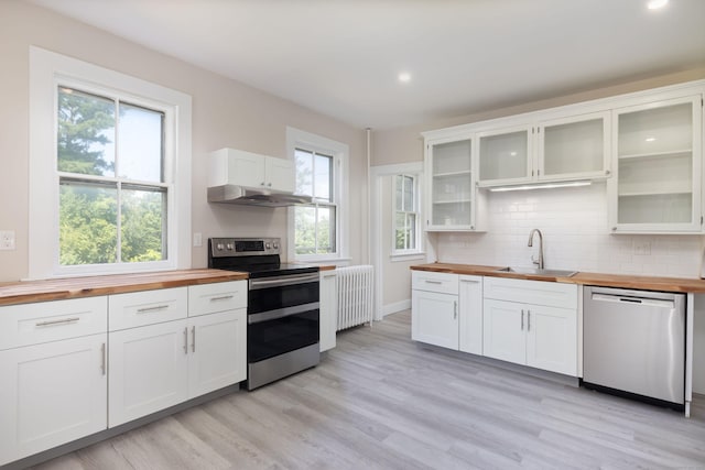 kitchen with a sink, wood counters, appliances with stainless steel finishes, light wood-type flooring, and radiator