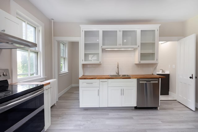 kitchen featuring plenty of natural light, butcher block counters, appliances with stainless steel finishes, a sink, and backsplash