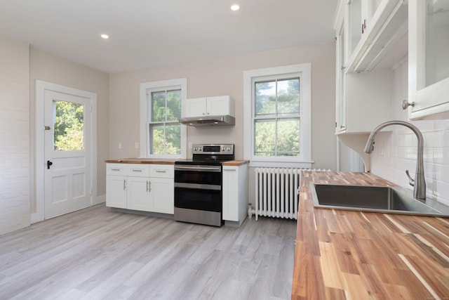 kitchen featuring butcher block counters, a sink, white cabinets, electric stove, and radiator heating unit