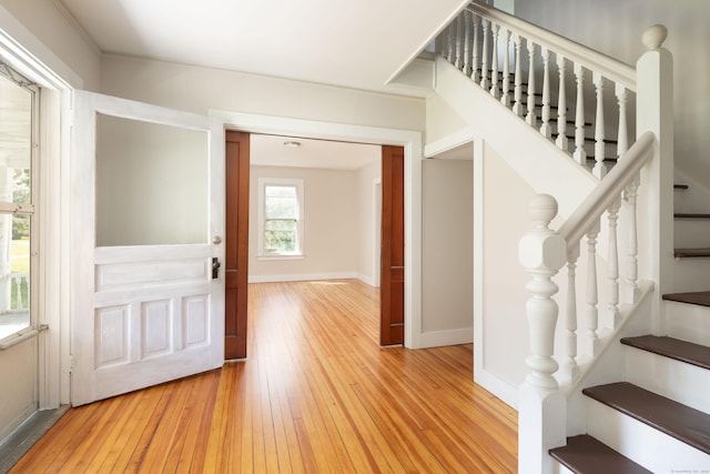 entryway with stairs, light wood finished floors, and baseboards