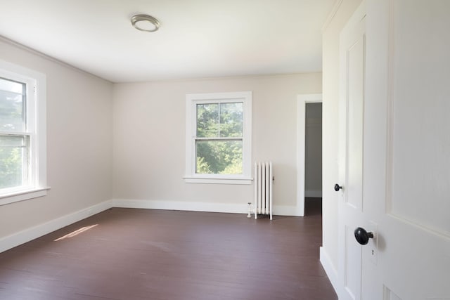 unfurnished room featuring baseboards, dark wood finished floors, and radiator