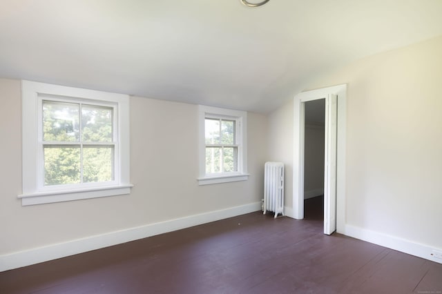 empty room with baseboards, dark wood-style flooring, plenty of natural light, and radiator