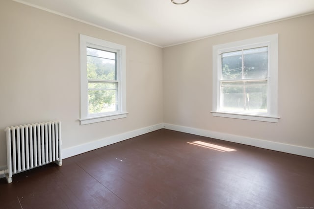 spare room featuring baseboards, crown molding, dark wood finished floors, and radiator