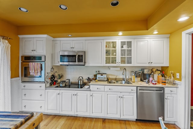 110 William St, Norwalk, CT 06851 - kitchen featuring stainless steel appliances, a sink, light countertops, white cabinetry, and glass insert cabinets