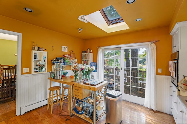 interior space featuring a baseboard radiator, light wood-type flooring, and a skylight