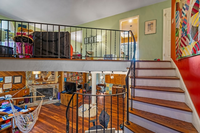 stairway with hardwood / wood-style flooring and a stone fireplace