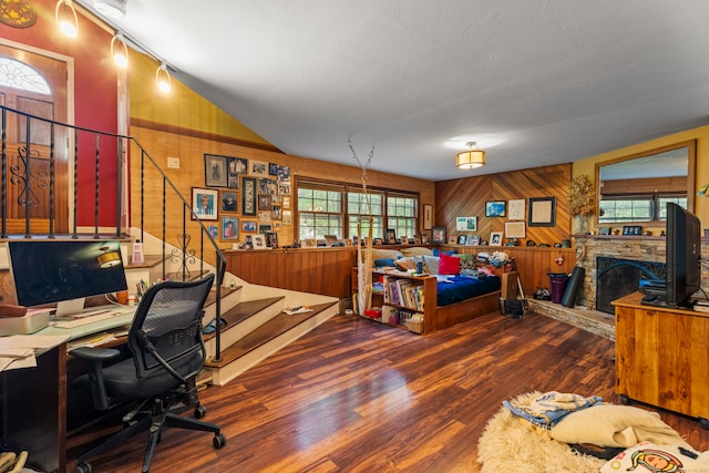 home office featuring wood walls, plenty of natural light, a fireplace, and dark hardwood / wood-style flooring