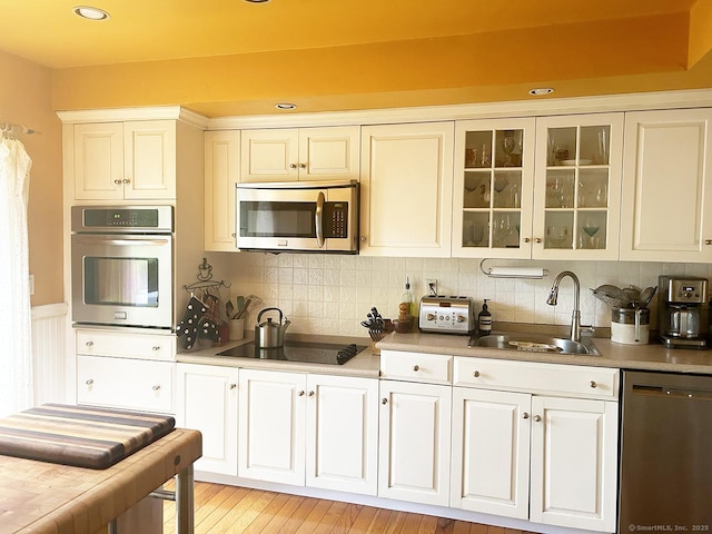 110 William St, Norwalk, CT 06851 - kitchen with appliances with stainless steel finishes, decorative backsplash, glass insert cabinets, light wood-style flooring, and recessed lighting