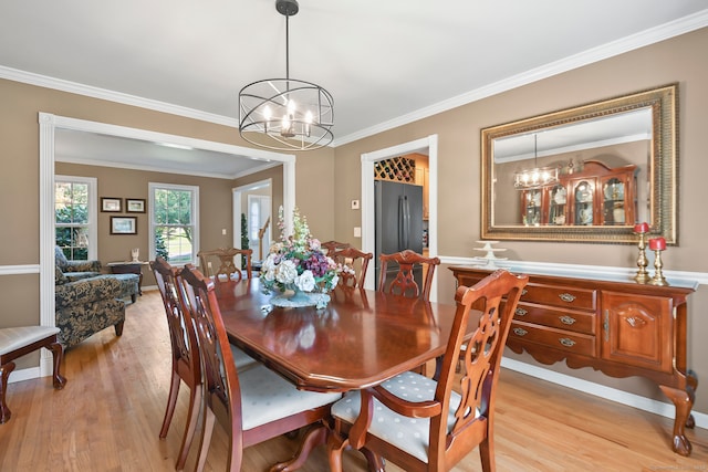 dining area featuring a notable chandelier, light hardwood / wood-style floors, and crown molding