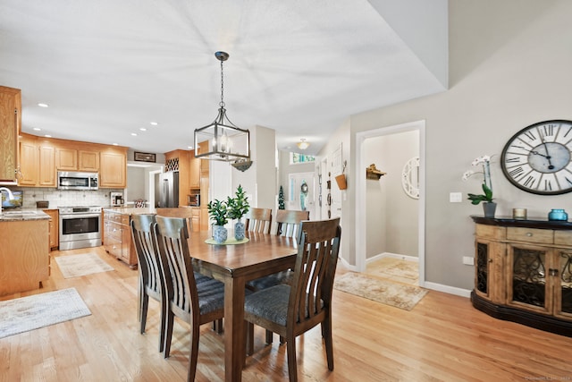 dining space featuring sink, light hardwood / wood-style flooring, and an inviting chandelier