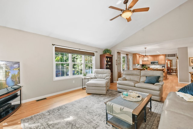 living room featuring light hardwood / wood-style floors, high vaulted ceiling, and ceiling fan