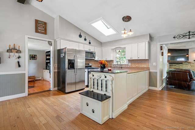 kitchen with white cabinetry, decorative light fixtures, stainless steel appliances, and light wood-type flooring