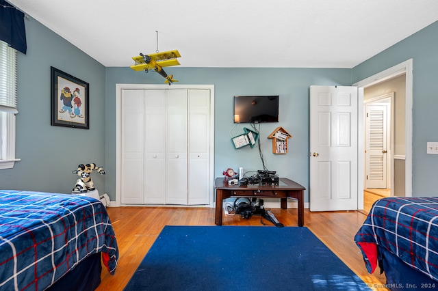 bedroom featuring a closet, wood-type flooring, and baseboard heating