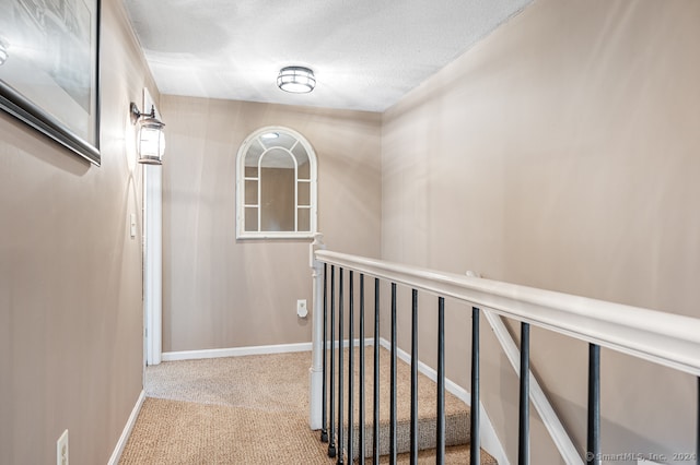 corridor with light carpet and a textured ceiling