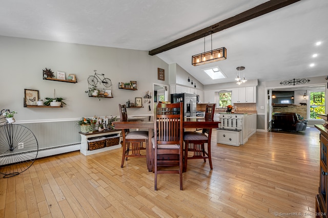 dining room featuring lofted ceiling with skylight, a baseboard radiator, light wood-type flooring, and an inviting chandelier