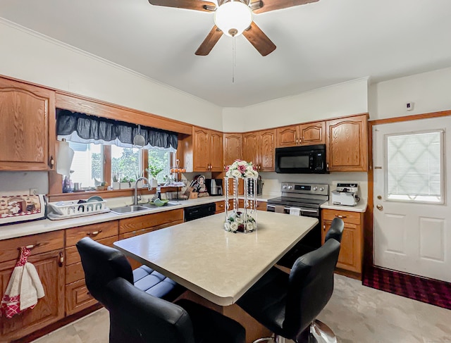 kitchen with a center island, sink, black appliances, ceiling fan, and a breakfast bar