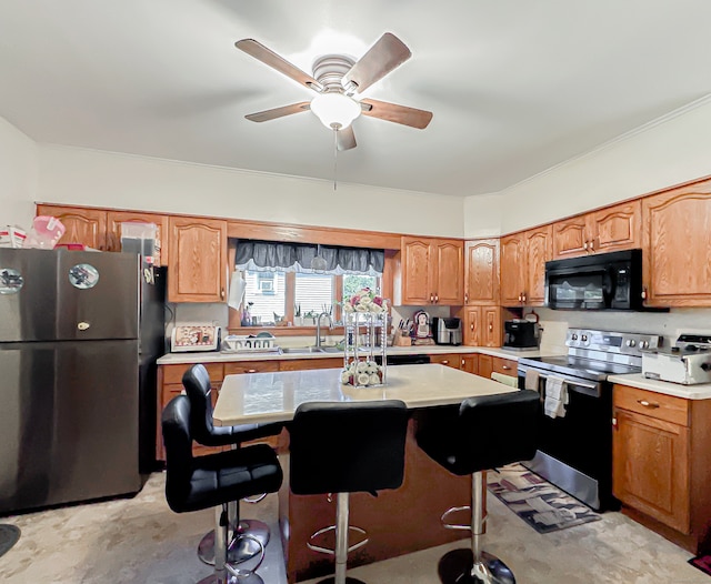 kitchen featuring a center island, appliances with stainless steel finishes, sink, ceiling fan, and a breakfast bar